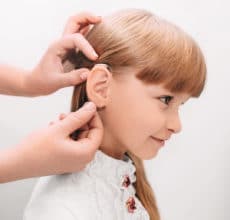 Doctor putting an hearing aid in a child's ear
