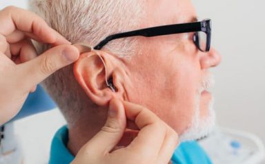 patient is assisted in setting up the hearing aid. Treatment of hearing of elderly people using a hearing aid.