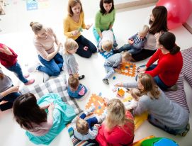Children with mothers sit in a circle and study colors, numbers and figures in the kindergarten